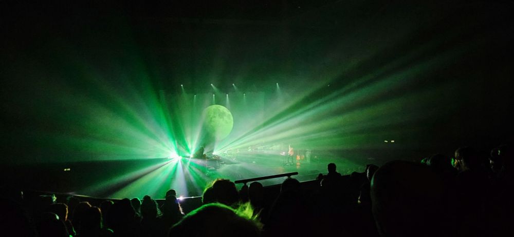 Band on stage, lightshow, moon projection.