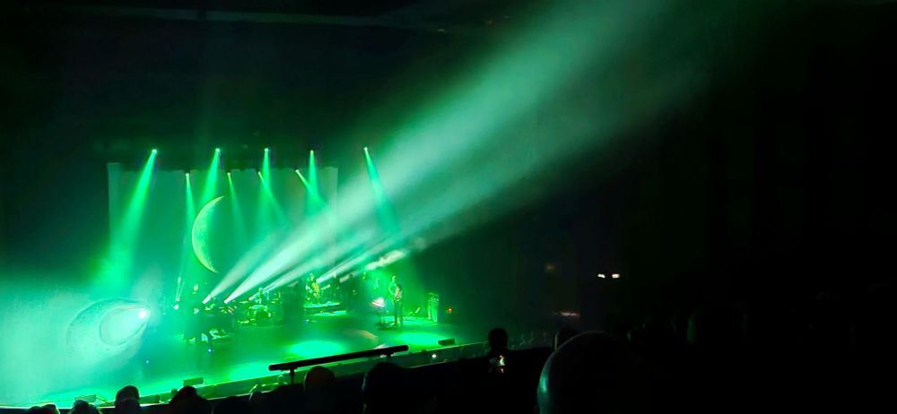 Band on stage, lightshow, moon projection.