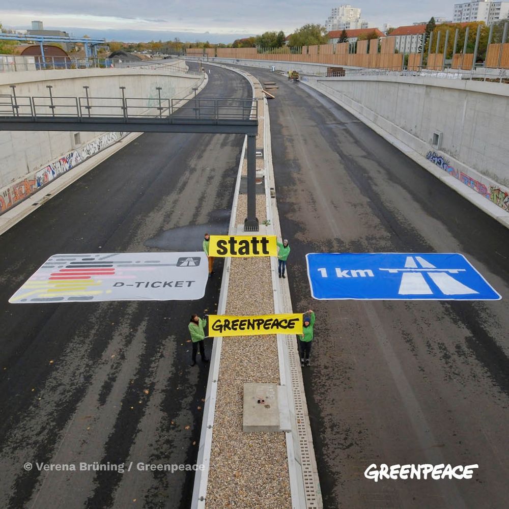 Greenpeace-Menschen halten Banner hoch, auf denen steht: Deutschlandticket statt 1 Km Autobahn
