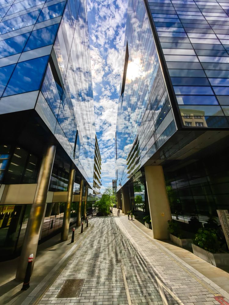 The sky reflected off two glass buildings on either side of an alleyway
