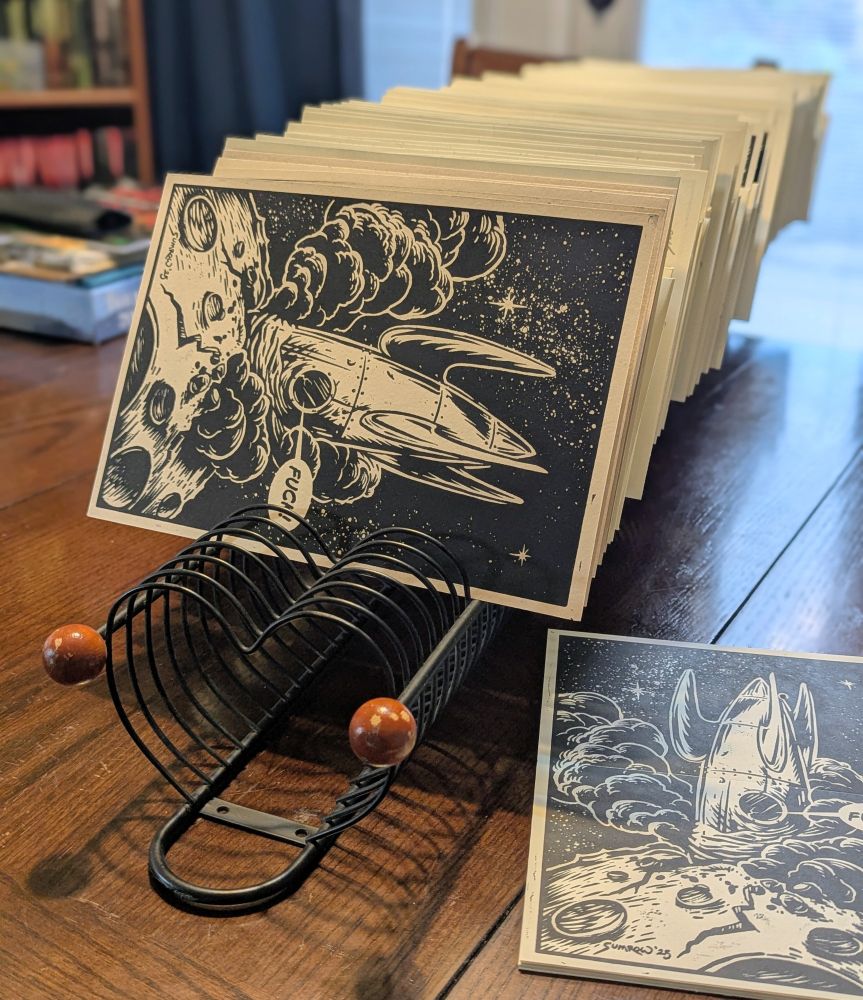 A CD tower on its side full of linocut prints of a space ship crash. 