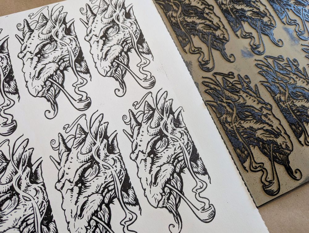 A hand pulled paper print from a linoleum block of a dragon smoking a pipe. 