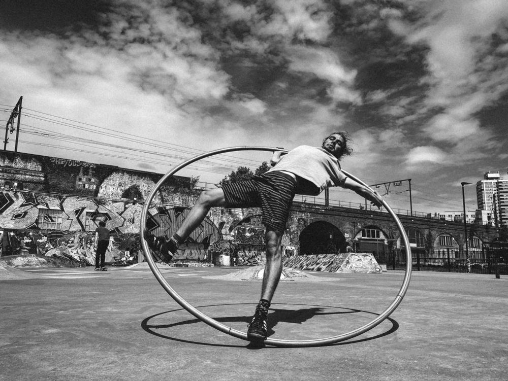 Black and white phone of an acrobat in a cyr wheel in a skate park