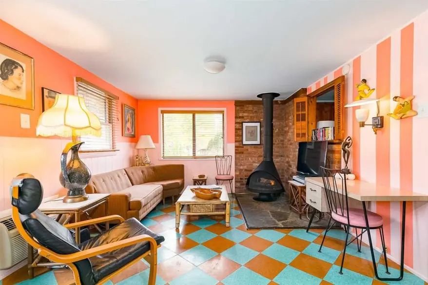 Another sitting area, with a fire, large lamp, and a pink and orange-striped wall