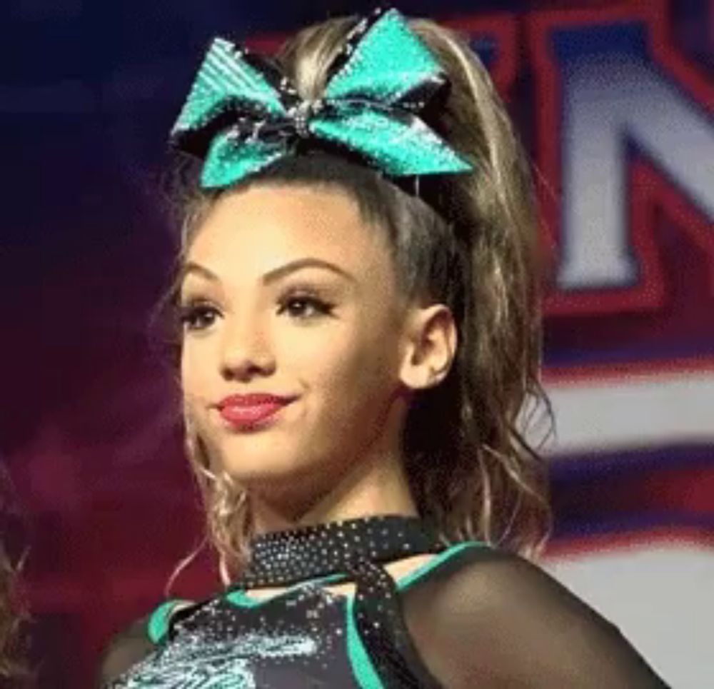 a cheerleader is wearing a green bow in her hair .