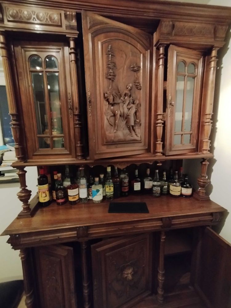 A Henry II buffet cabinet with bottles of rum. It's a big ornate antique-y wooden cabinet with a carving of a guy on a horse on the main cabinet door.