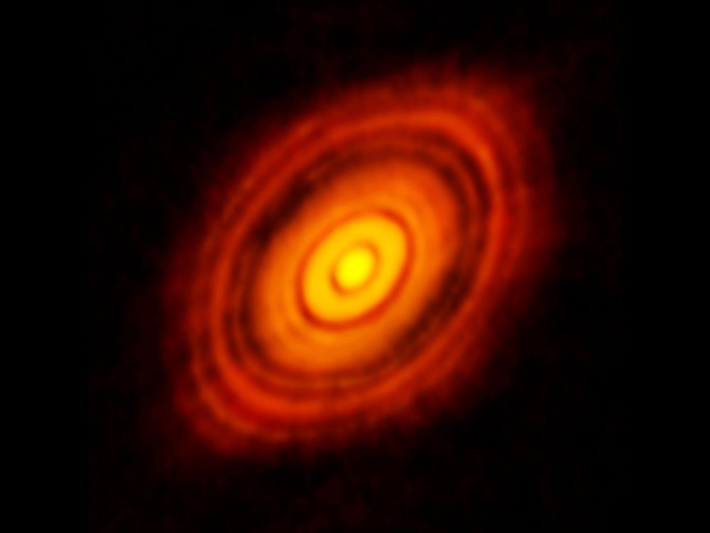 A 2014 ALMA image of the Class I Young Stellar Object HL Tau. Image is an red-orange-yellow disk on a black field. The disk has alternating light and dark (black) rings, indicating gaps in the disk. The light gets brighter (more orange-yellow) as you look towards the center. It is canted at an angle. Image credit: NRAO/ESO/NAOJ