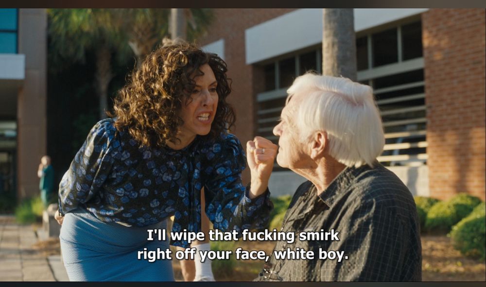 Picture of Judy Gemstone brandishing a fist at an old man with the caption “I’ll wipe that fucking smirk off your face white boy” 