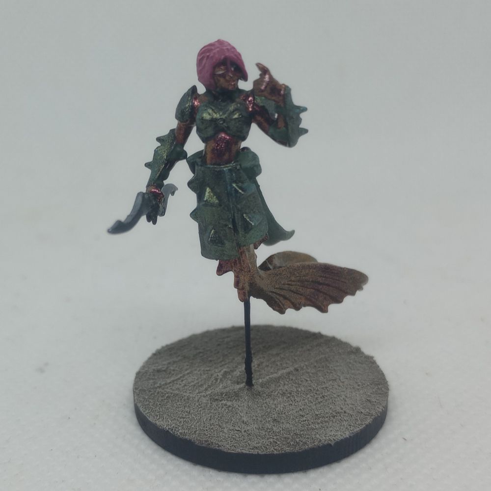 A mermaid with metallic red orange skin, blueish green armor and pink hair.