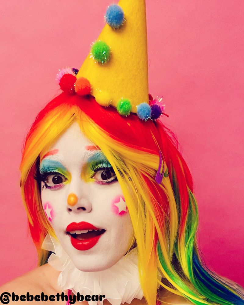 Vibrant rainbow haired clown maiden strikes a surprised smile 