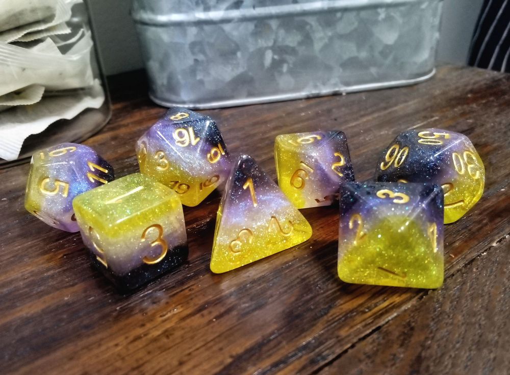 A set of gaming dice in the non-binary pride flag colours of yellow, white, purple, and black, with more glitter inside than n orgy in the faerie realm.