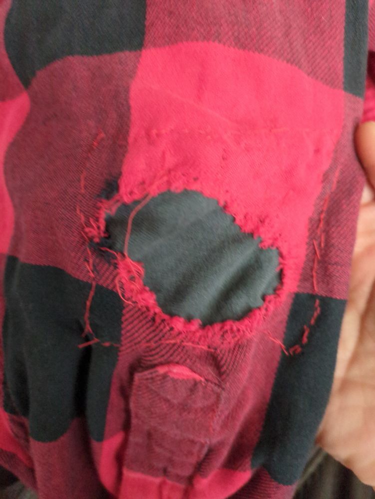 A sleeve of red and black flannel shirt with a hole that's been patched with dark gray fabric (it was the closest I could get to the actual fabric color without going out and buying more fabric).