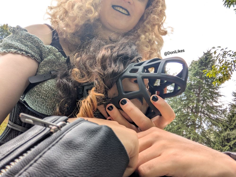 Two girls in a selfie.  One has her hand cupping the dog muzzle of the other as she rests on her.