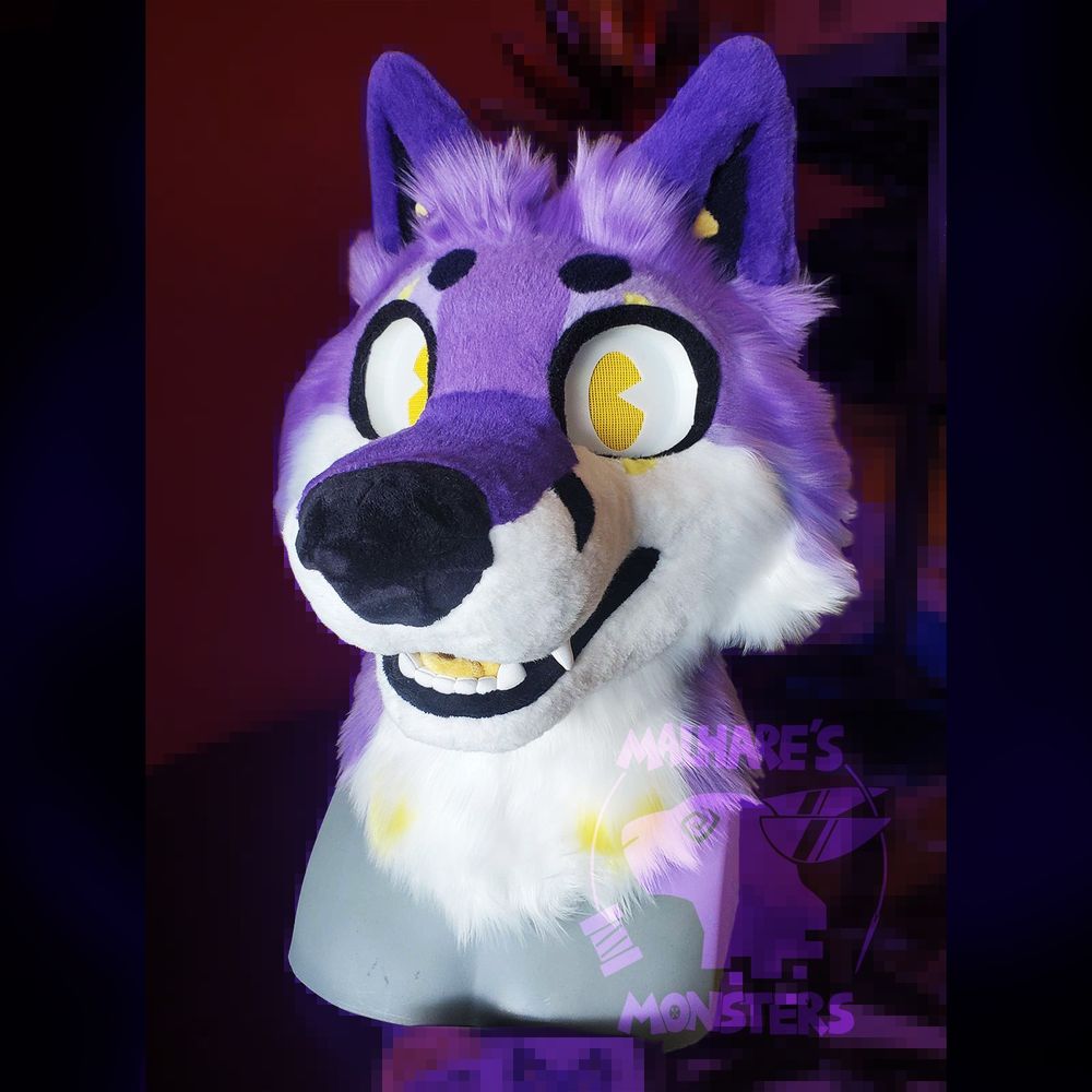 A purple and white fox fursuit with yellow and black crescent moon details, viewed at a 3/4 view.