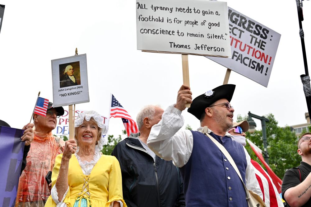 Man in tricorn hat at a No Kings protest holding a sign. 
