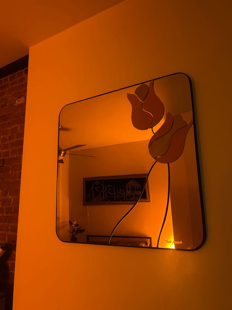 The David Marshall mirror hung up in an amber lit room 