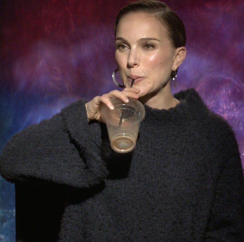 Natalie Portman drinking an iced coffee with a smirk on her face 