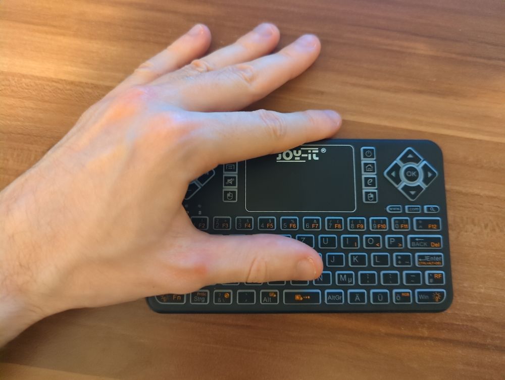 photo of a very small keyboard with a hand on top for comparison. the hand's thumb rests on the letter keys, covering up all 3 rows.