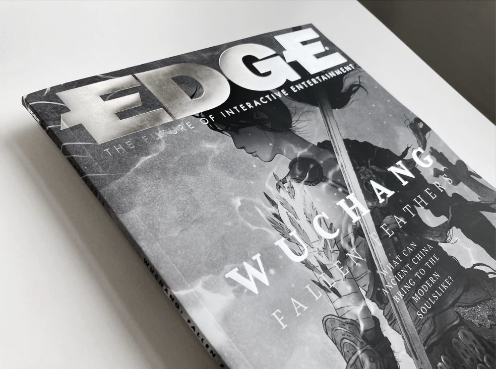 An angled photo of the cover of Issue 407 of EDGE, which features bespoke black and white artwork for WUCHANG: Fallen Feathers.