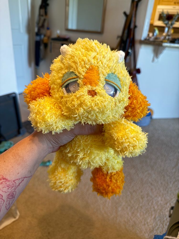 Yellow and orange fluffy plushies with little white horns and sparkly eyes