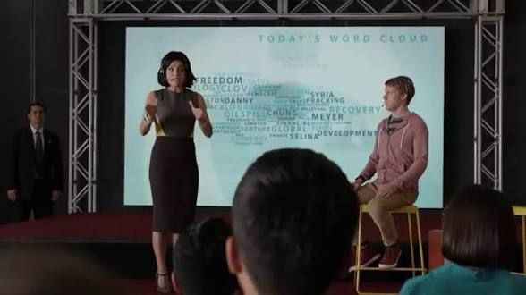 Screenshot to the “Clovis” episode of Veep with Julia Louis-Dreyfus as Selina Meyer on stage with Clovis founder in front of today’s word cloud presentation.