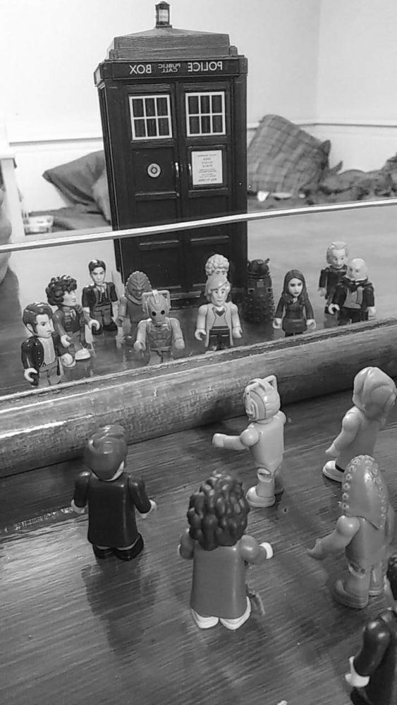 Black and white image of a police phone box, with Lego characters from the TV series Doctor Who,  reflected in a mirror. 