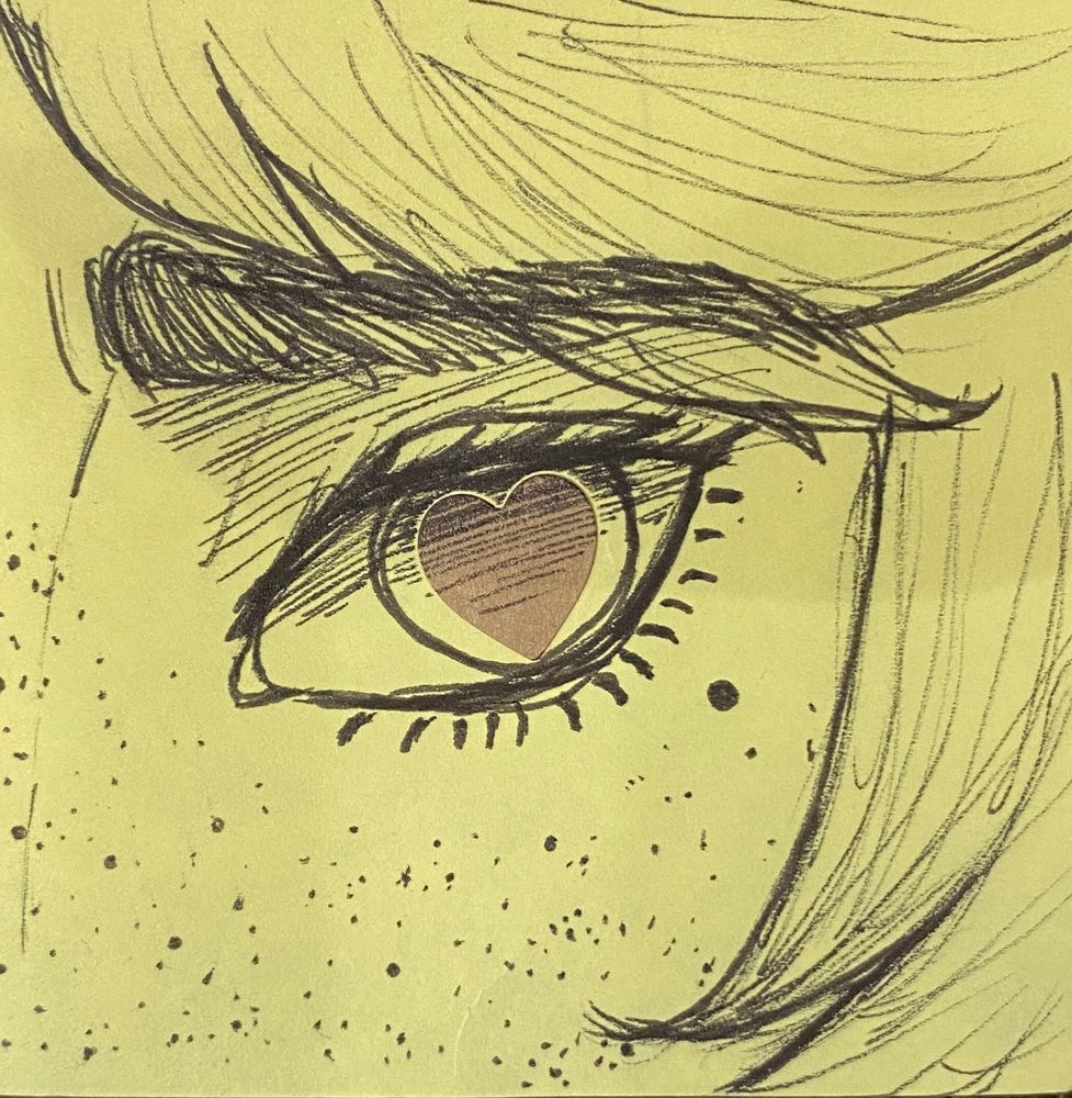Close-up of Dirk’s eye with a heart pupil on a yellow sticky note. The heart is a brown matte sticker. 