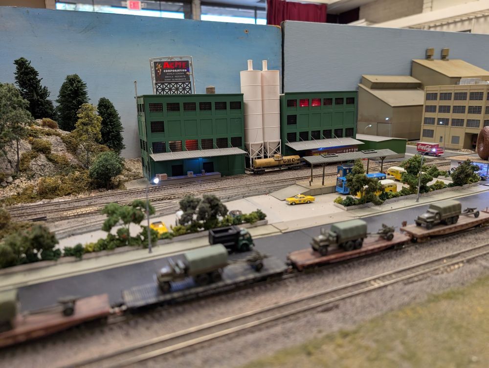 A military train passes by a warehouse for the ACME corporation