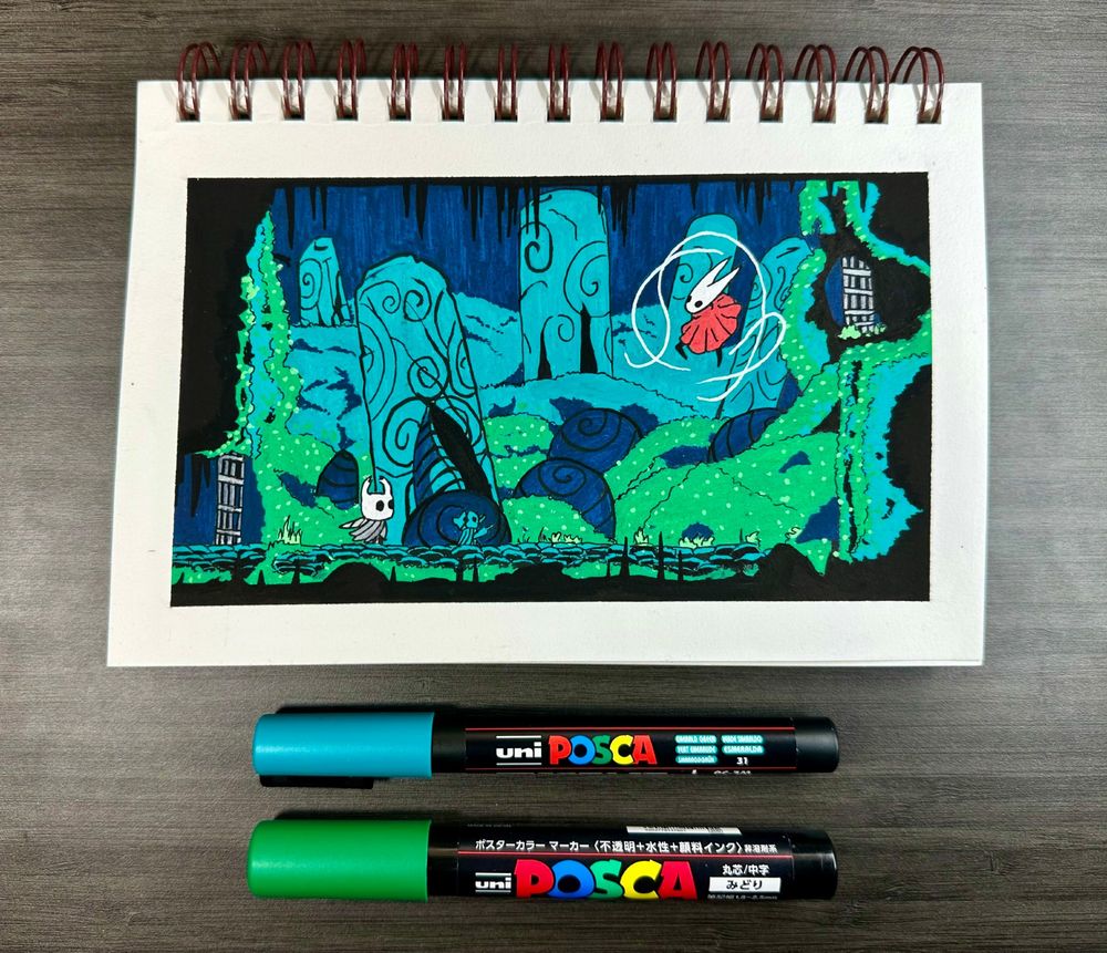 Photo of notebook with a posca drawing of Hornet and The Knight from Hollow Night on it, two markers lay underneath the book