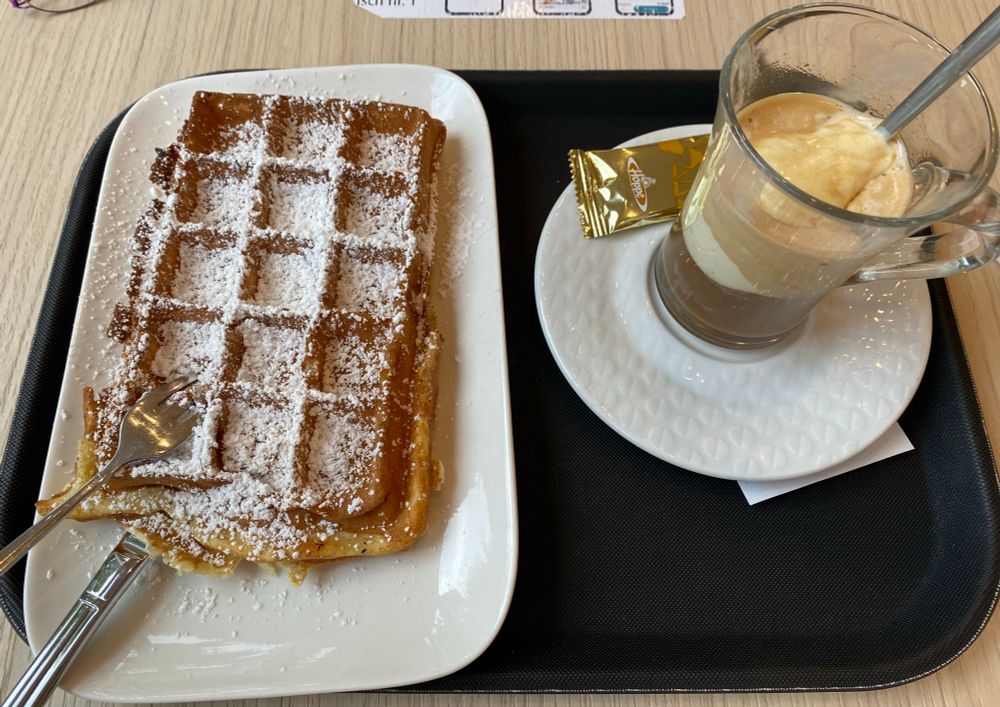 Eine Waffel mit Puderzucker, daneben ein Eiskaffee