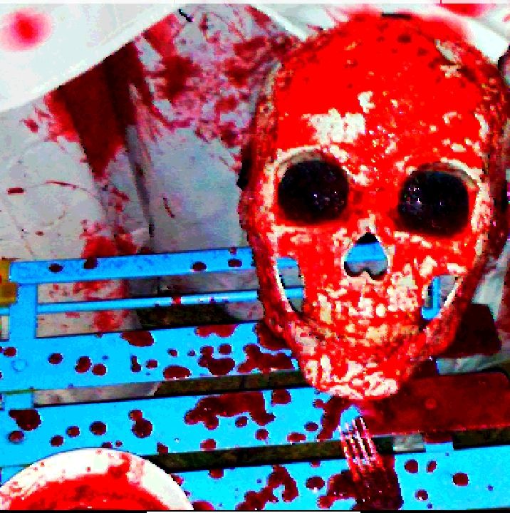 a blood covered skull (bright red on white), sky blue metal slat chair, and white shirt. a bloody fork shining with dark blood. its from the HOW TO MAKE BLOOD page on my website! coming soon to my ko-fi!