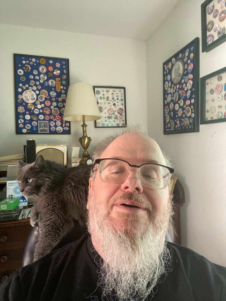 Me with cat on back of chair with some of my Dad’s political buttons and desk in background 