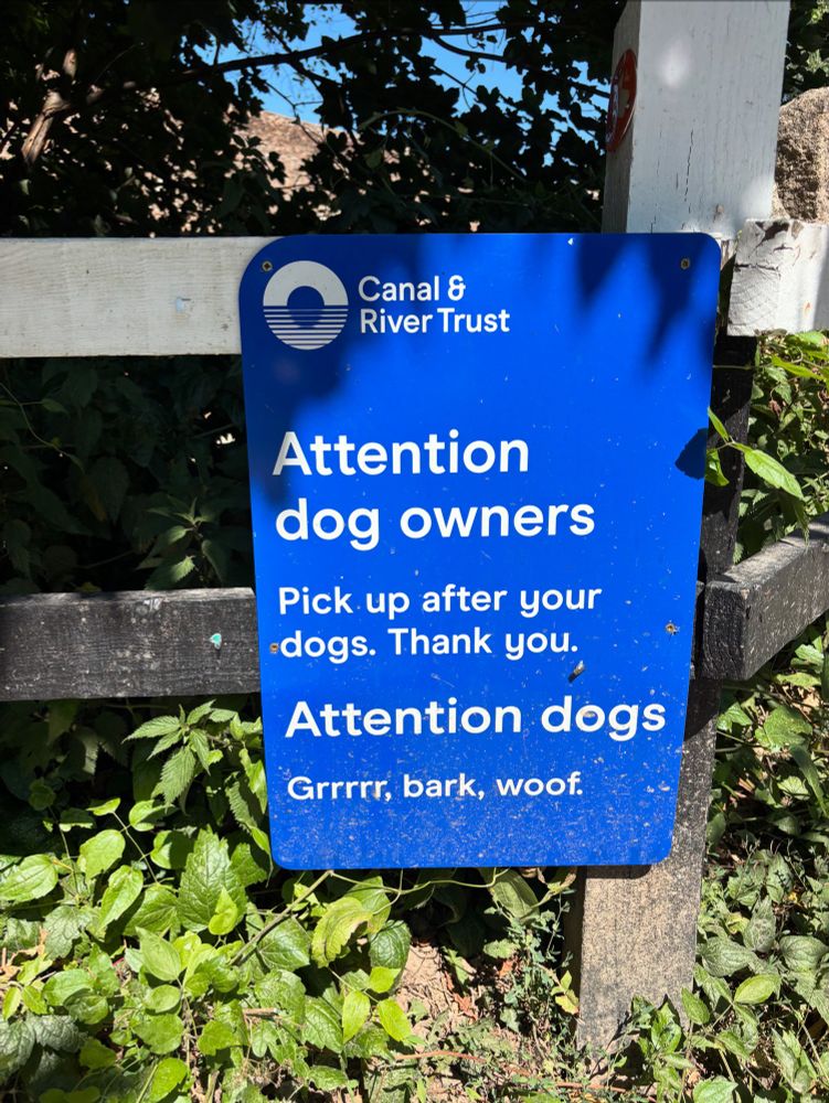 A blue sign nailed to a low fence on the Kennet and Avon canal in Bradford-on-Avon, Wiltshire, photographed on a sunny afternoon: 

Attention dog owners:
Pick up after your dogs.
Thank you.

Attention dogs:
Grrr, bark, woof.