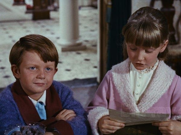 The little children from "Mary Poppins" presenting their job listing for a nanny. Michael listens with satisfaction as Jane sings "love us as a son and daughter...and never smell of barley water," whereupon he proudly announces, "That's the part I put in!"