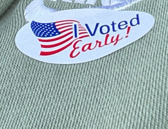 Close up of I voted early sticker with American flag on green sweatshirt