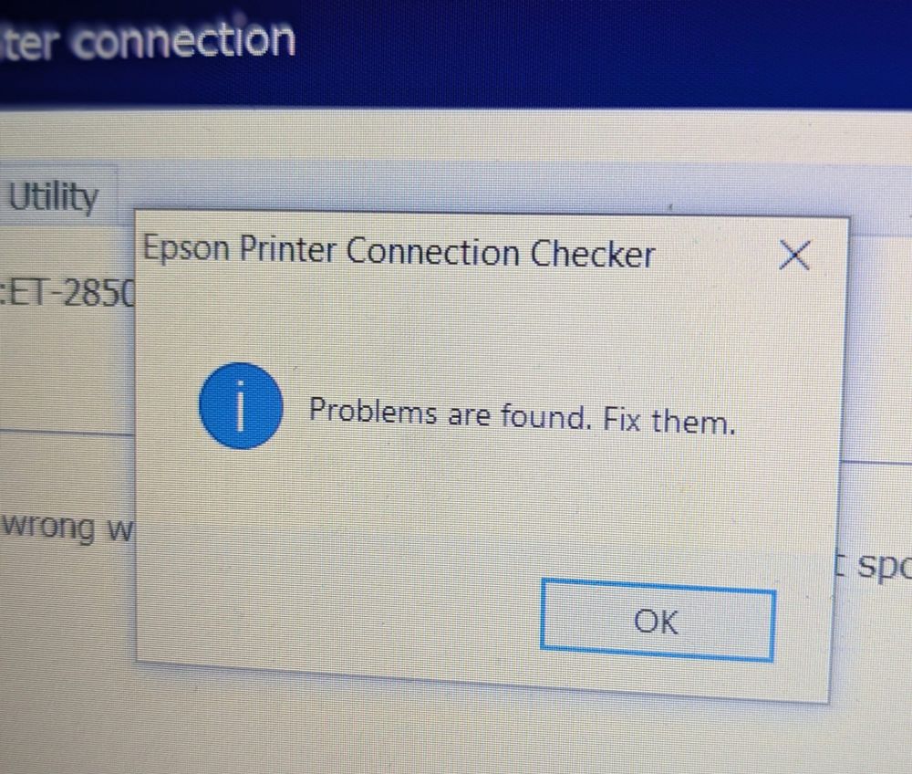 A photo of my computer screen. On it is a window that has 'Epson Printer Connection Checker' as a header bar, then a blue circle with an exclamation mark inside. Next to that are the words 'Problems are found. Fix them.' 