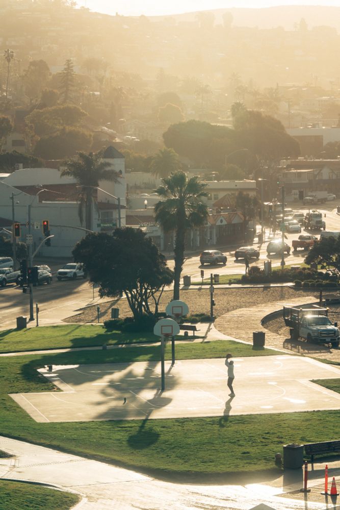 Outdoor basketball courts at Laguna Beach, set against the backdrop of the Pacific Ocean and coastal cliffs. 