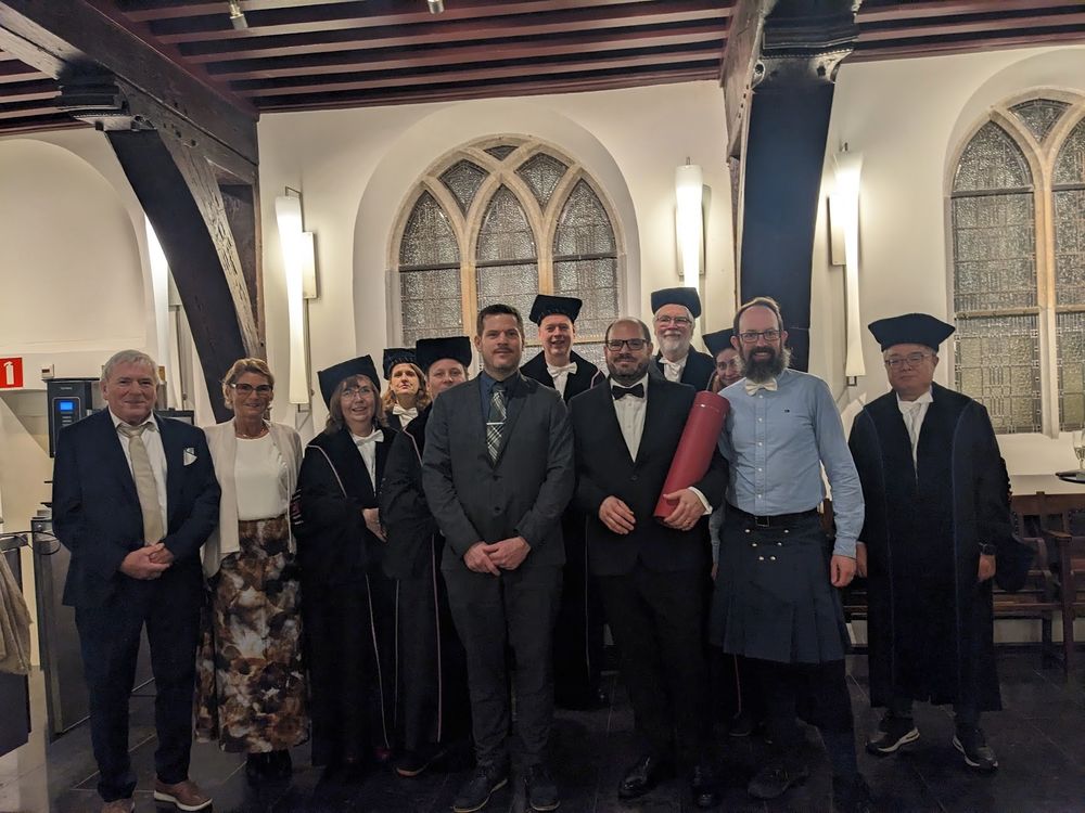 Crowd of smartly dressed people in old building, including Stian holding his award.