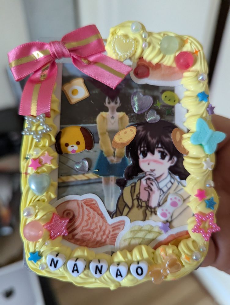 A decorated top loader featuring the character Nanao from Robot Alchemical Drive! It's bright yellow and features lots of bread stickers and puppy stickers 