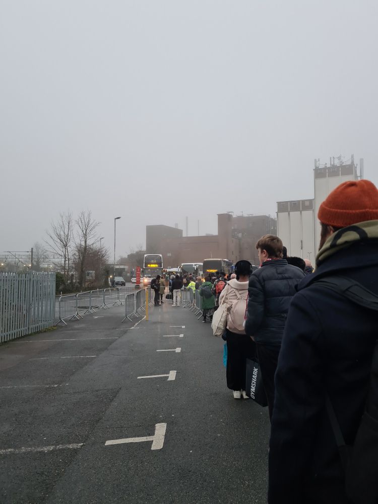 Very long line of people at a bus stop