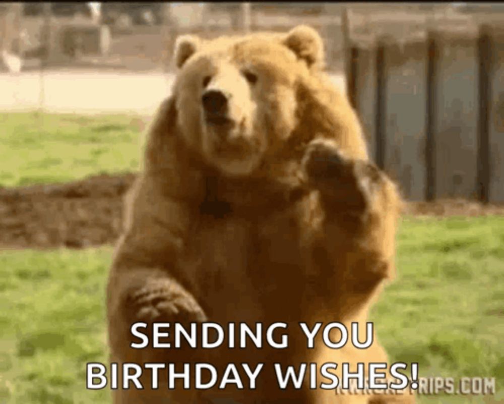 a brown bear is standing on its hind legs in a field and sending you birthday wishes .