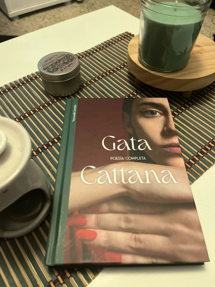 Imagen en la que aparece el libro poesías completa de Gata Cattana sobre una mesita en la que hay una vela y un quemador de incienso