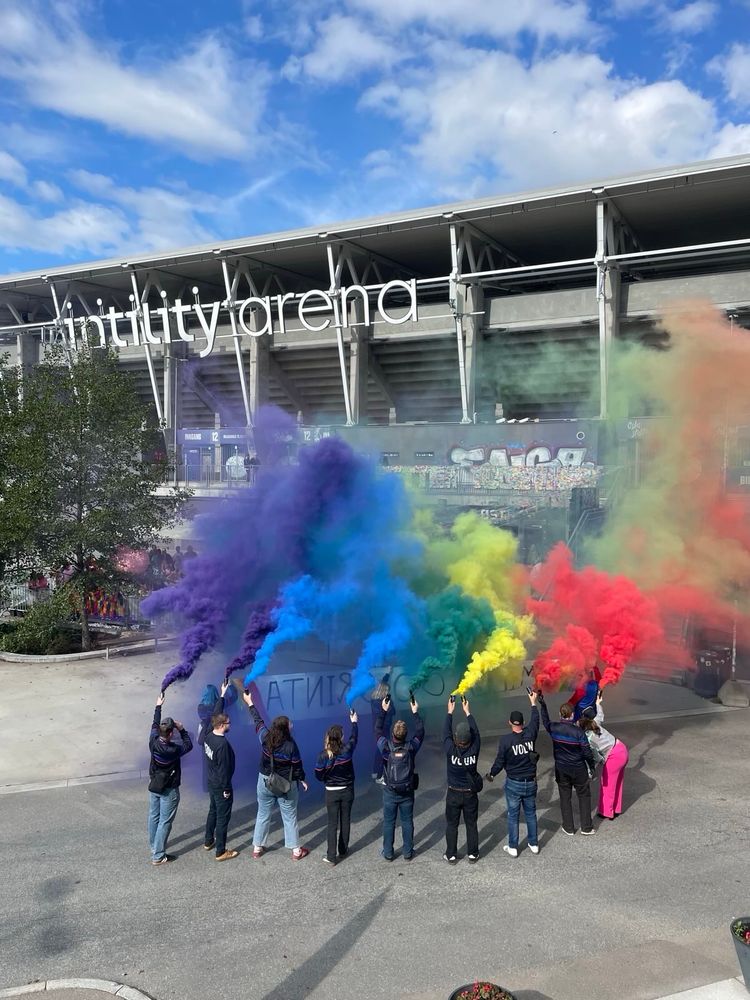 Bilde av en rekke mennesker som fyrer av røyk i regnbuens farger utenfor Vålerenga Stadion