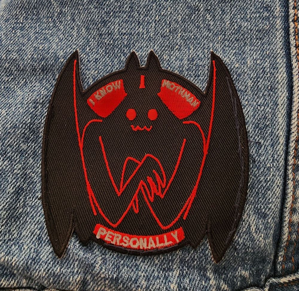 A patch of mothman. It says "I know mothman personally."
