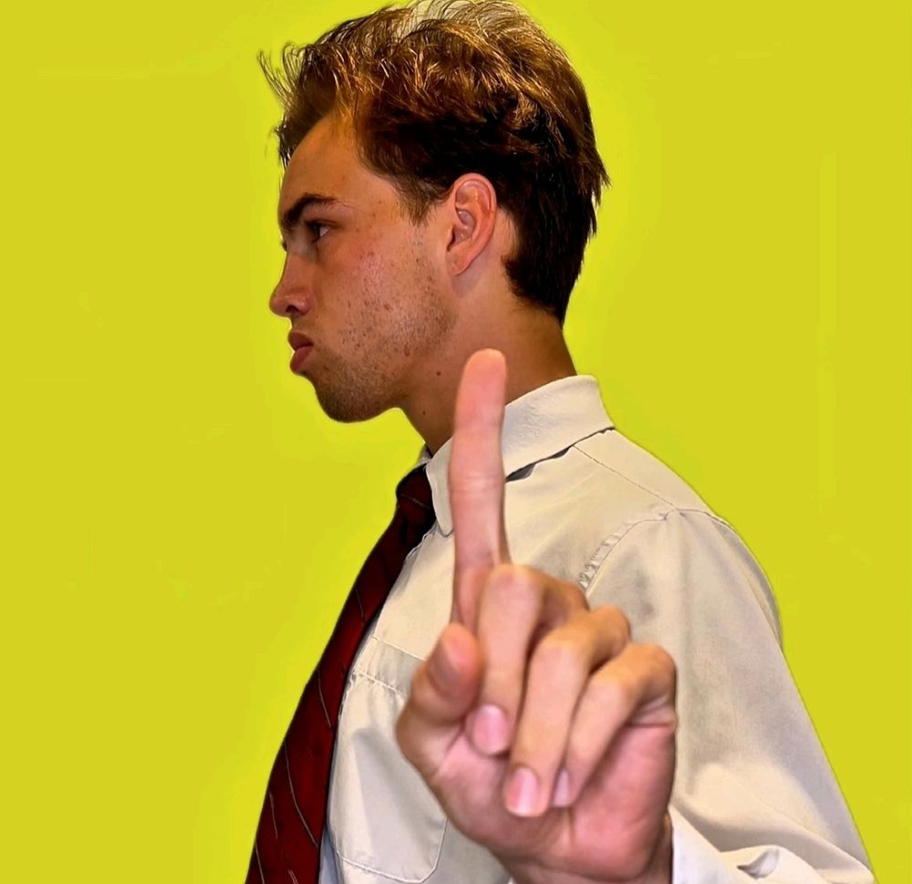  A man, looking away. He is making the one symbol to indicate "hold."