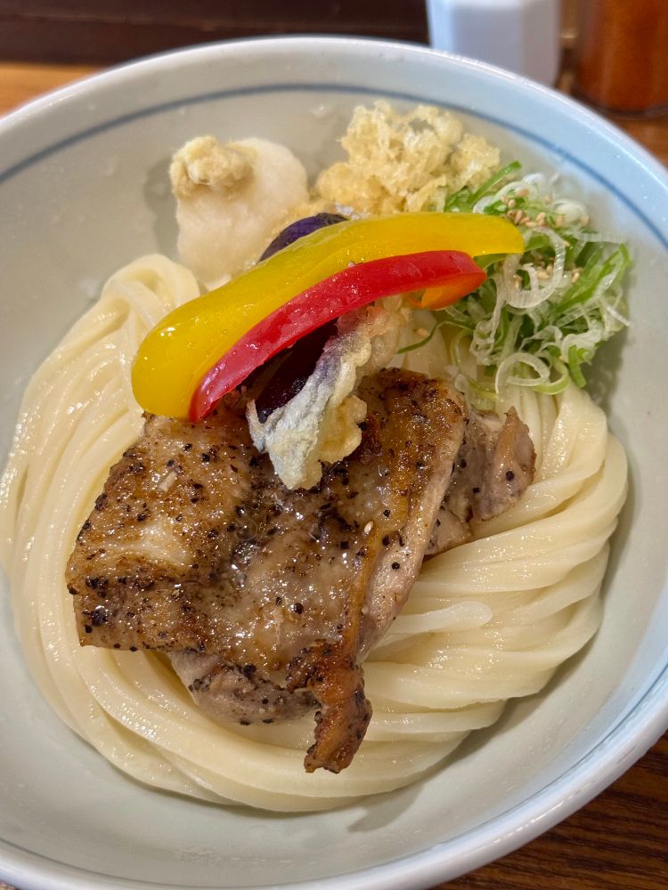 増田うどん 黒胡椒チキンぶっかけ(冷)
他には、パプリカ(黄・赤)と、なすの天ぷら、刻み長ネギ、揚げ玉、大根おろし、おろし生姜がトッピングされています。
揚げ玉は載せないことも可能です。
