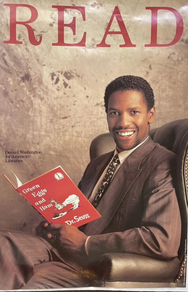 A smiling Denzel Washington holds the book Green Eggs and Ham while looking dapper as usual.