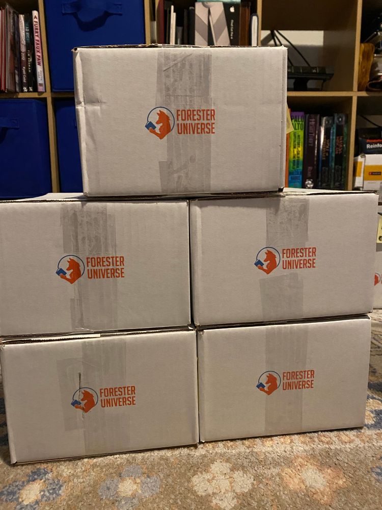 Stack of five white Forester Universe-branded cardboard boxes on a patterned carpet, with bookshelves in the background.