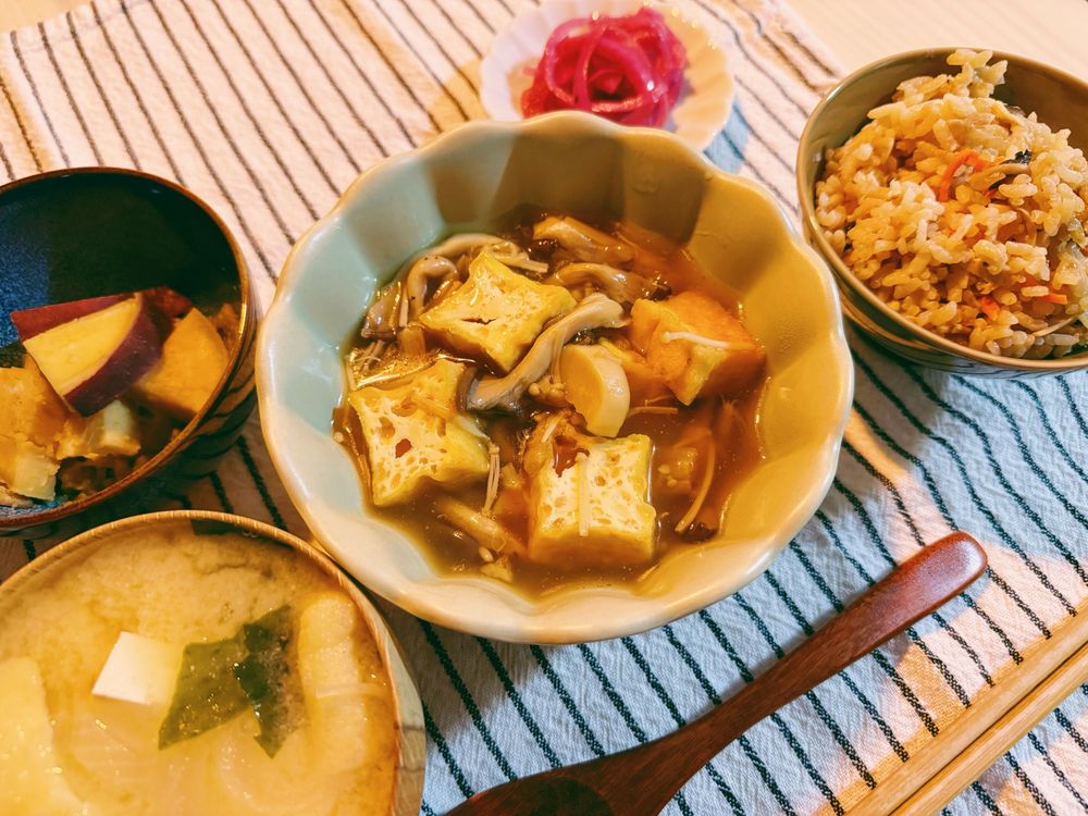 テーブルに並んだおゆはん。豆腐・油揚げ・ワカメと玉ねぎのお味噌汁、さつまいもの甘煮、紫玉ねぎのピクルス、きのこご飯、tofu puffときのこの煮込み。