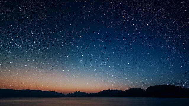 Starry sky stock photo over a landscape with a fading sunset